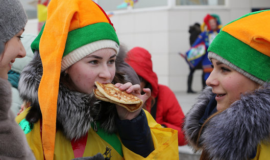 Участники кушают блины во время массового масленичного гуляния "Блинно-сырное веселье" в Белгороде