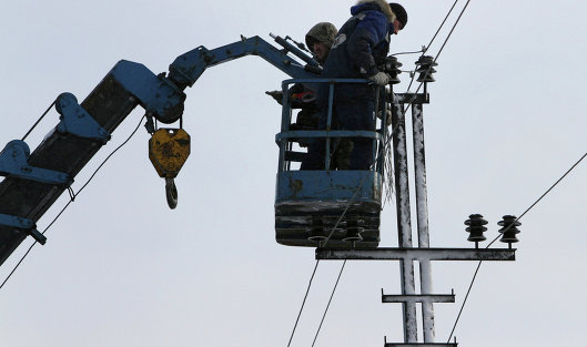 Монтеры крепят провода на новой опоре линии электропередачи