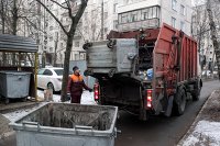 " Сотрудник коммунальных служб выгружает мусор из контейнера в мусоровоз