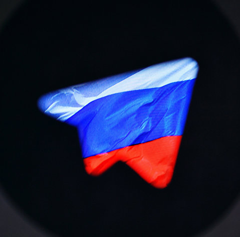 Логотип социальной сети "Телеграм" на фоне российского флага.