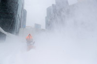 Сотрудник коммунальной службы убирает снег с площади у делового центра "Москва-сити"