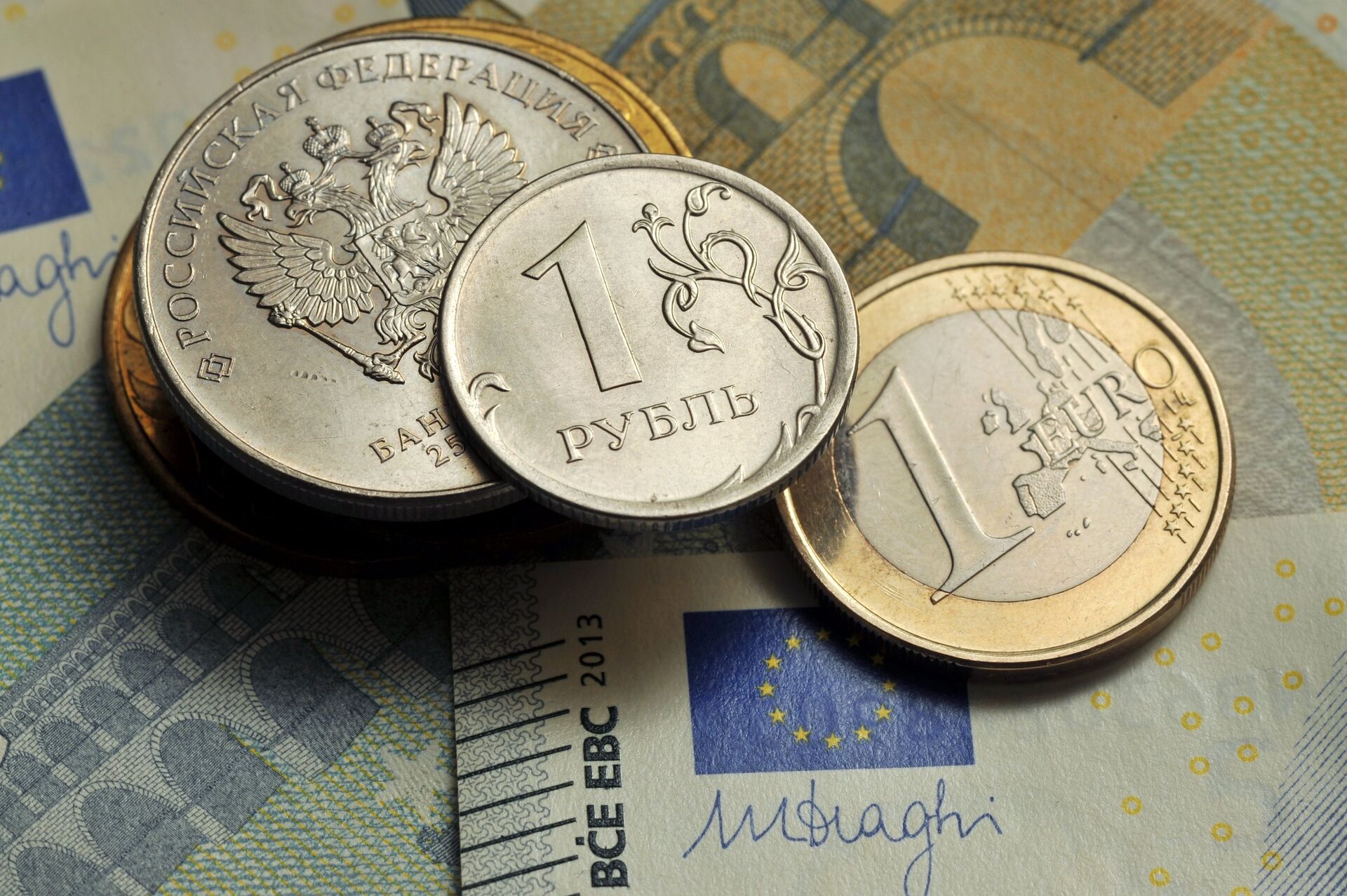 Монеты номиналом 1 рубль и 1 евро на фоне банкноты номиналом 5 евро - ПРАЙМ, 1920, 26.02.2021